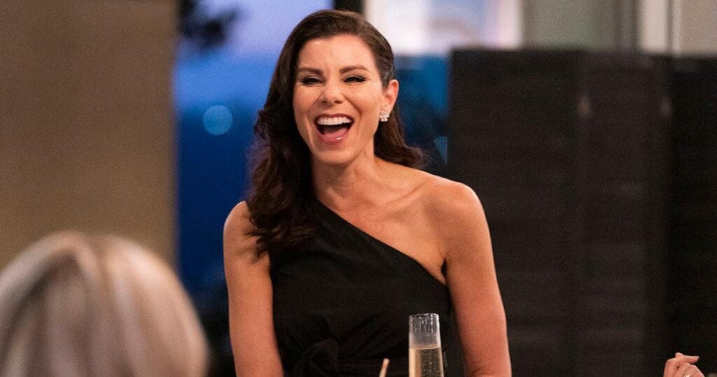 Heather Dubrow laughing in black one shoulder down while drinking champagne on RHOC